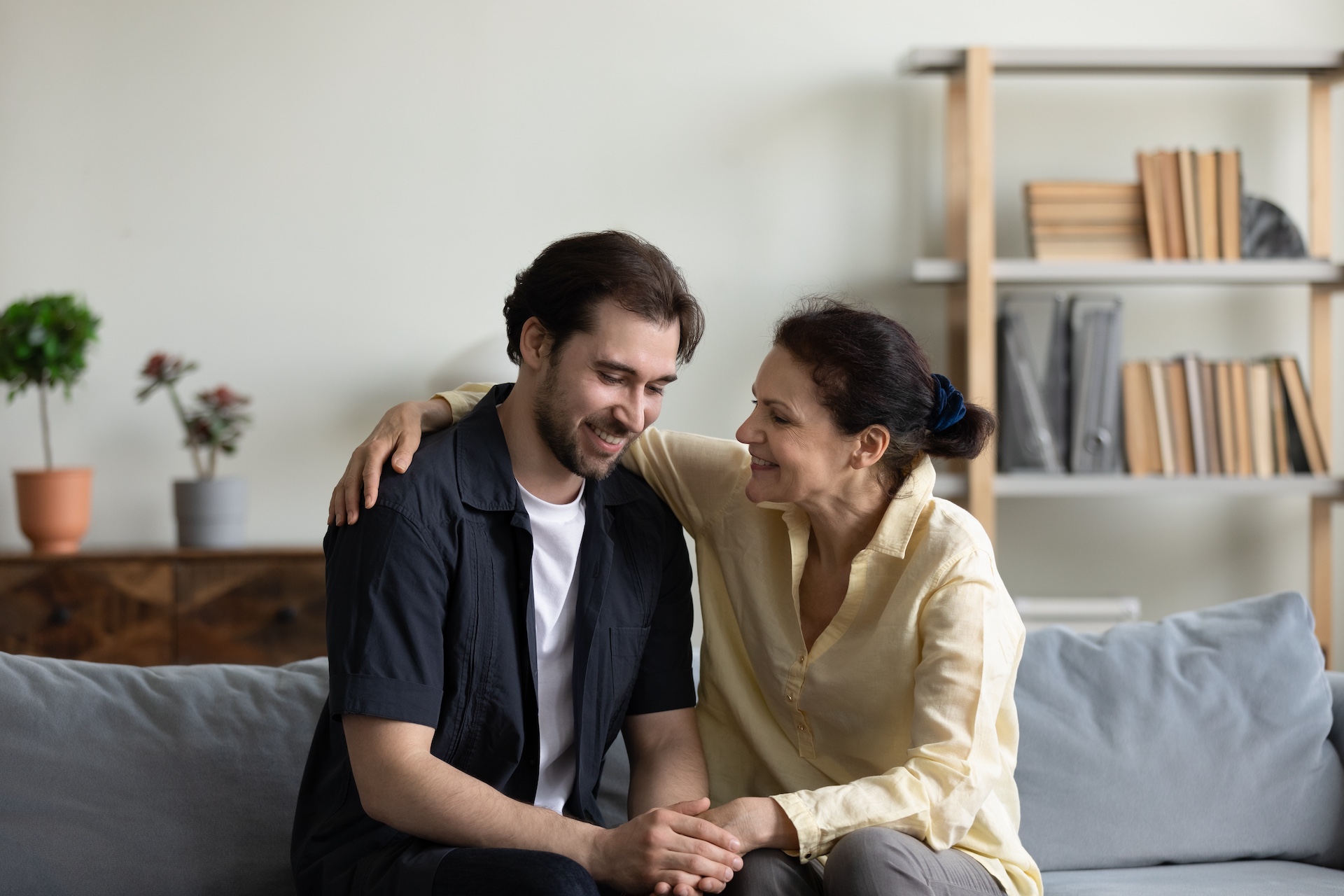 Happy,Old,Retired,Woman,Cuddling,Shoulder,Of,Grown,Smiling,Son,